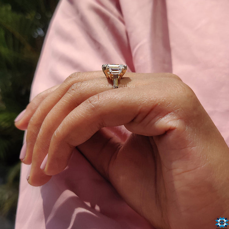 Yellow gold engagement ring with emerald cut and double prong setting.
