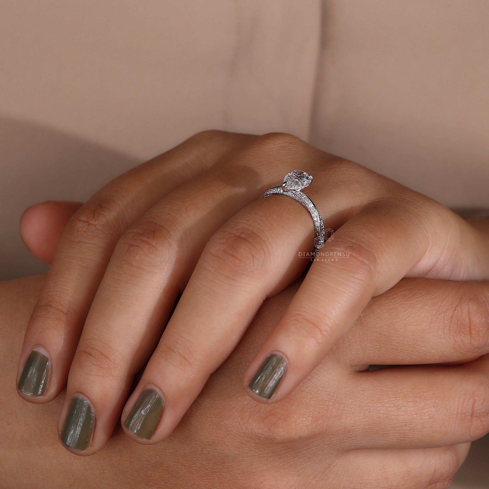 Model displaying a pear shaped diamond engagement ring with claw prongs.