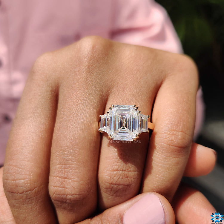 Engagement ring with trapezoid side stones and centre emerald cut moissanite.
