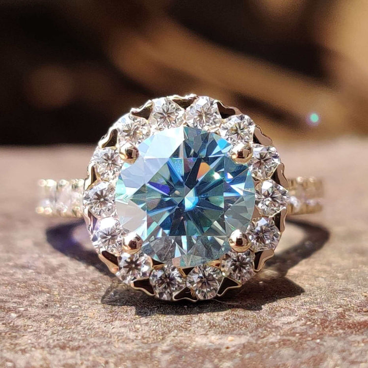 Round moissanite engagement ring with cyan blue center.

