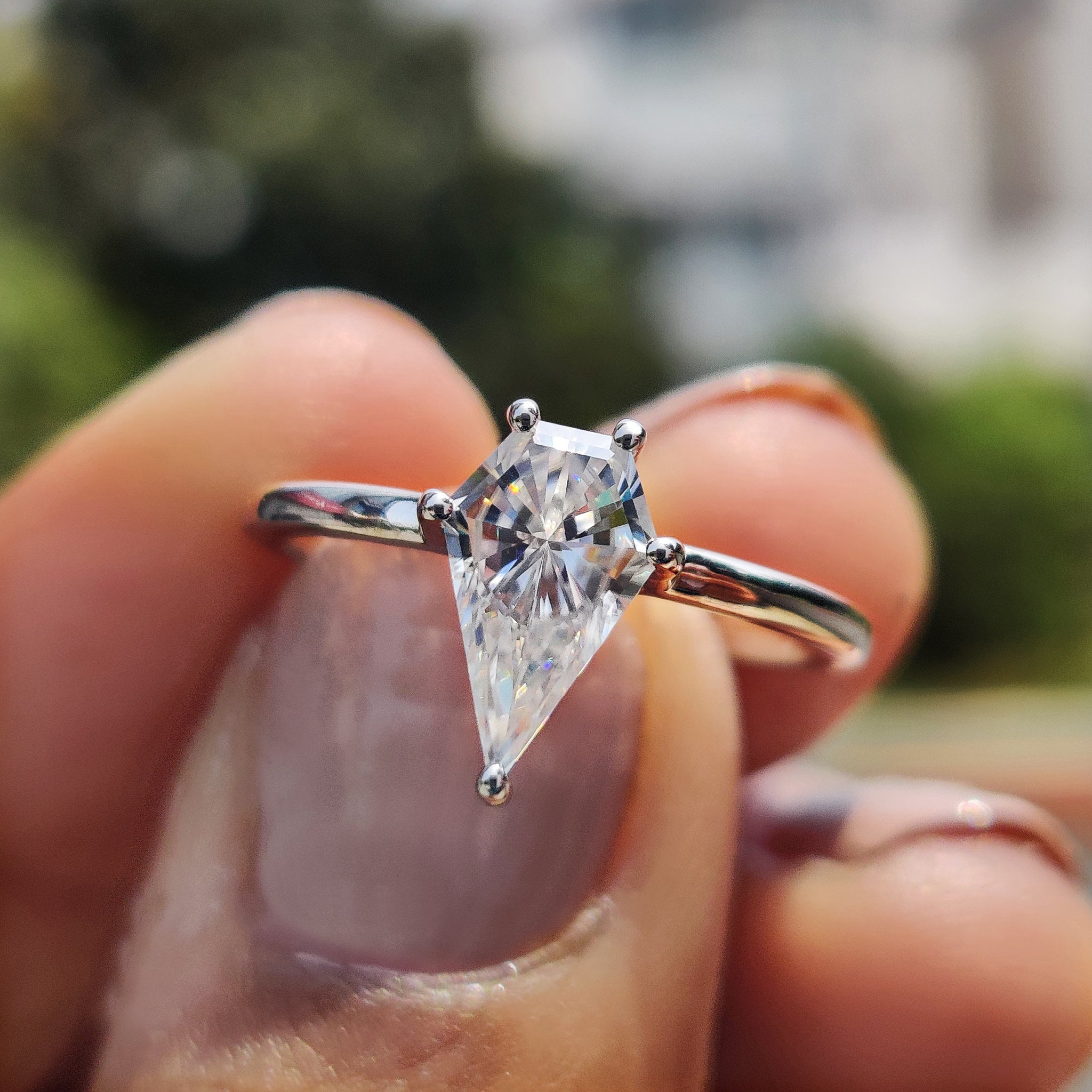 Moissanite solitaire ring featuring a spear cut stone in a prong setting.
