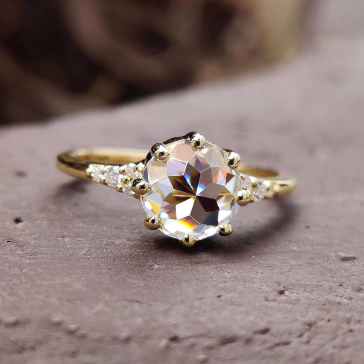 Rose cut engagement ring with a round moissanite in a yellow gold muse setting.
