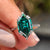 White gold moissanite ring featuring a Dutch marquise green centre stone.
