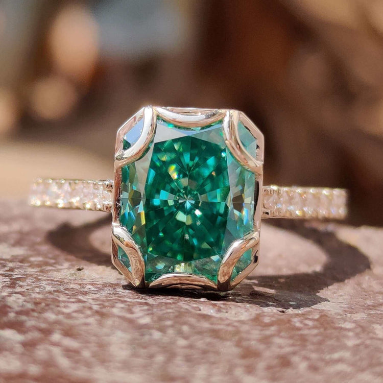 Green moissanite ring with radiant cut center stone.
