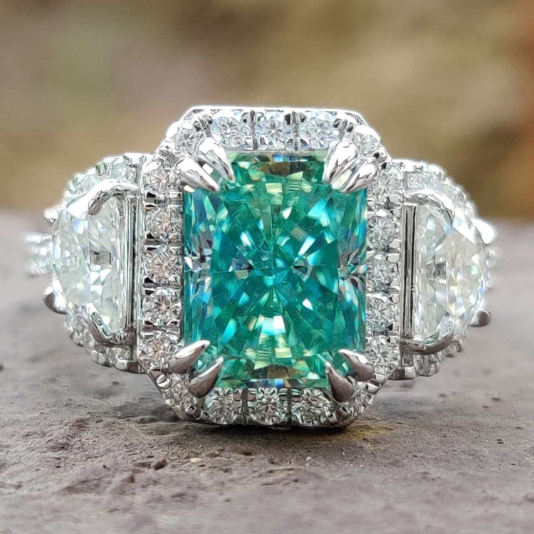 Three stone halo moissanite ring with cyan blue center.
