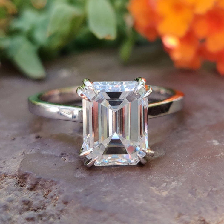 Emerald cut moissanite solitaire engagement ring in white gold.
