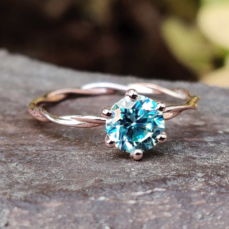 Round cut cyan blue moissanite ring in rose gold.
