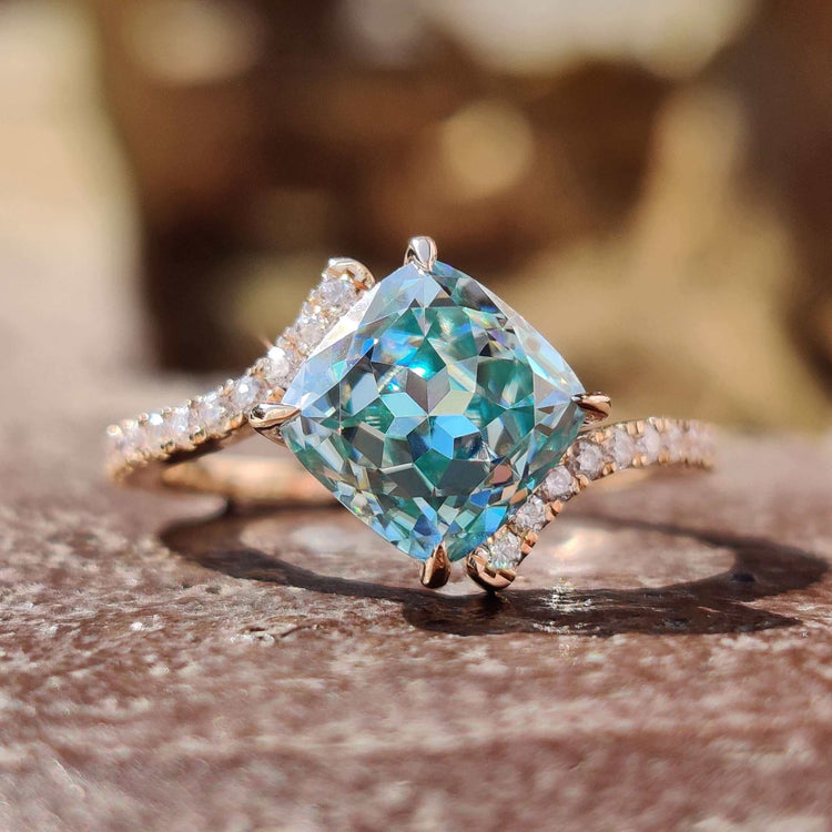 Cushion Rensu cut engagement ring with cyan blue moissanite center.
