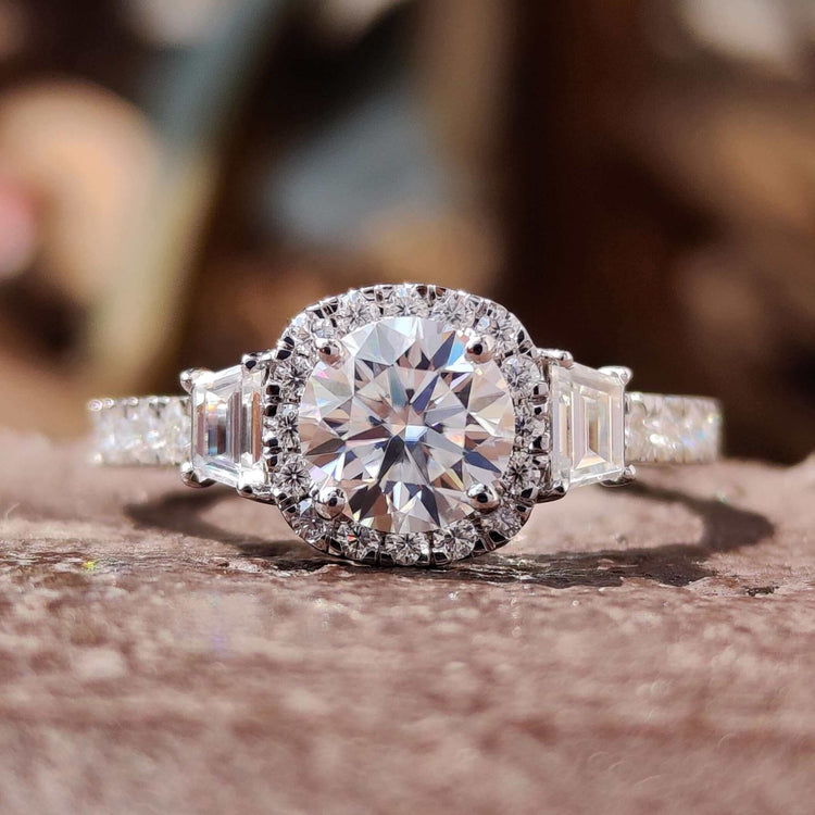 Round cut engagement ring with trapezoid side stones in a white gold setting.
