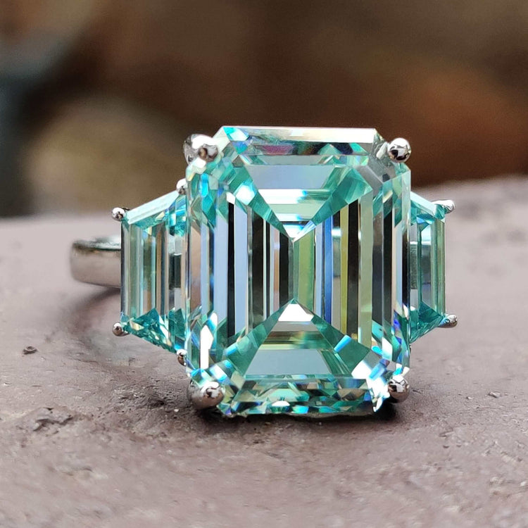 Emerald cut cyan blue moissanite ring in three stone design.
