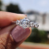 Hexagon engagement ring with round cut side stones in prong setting.
