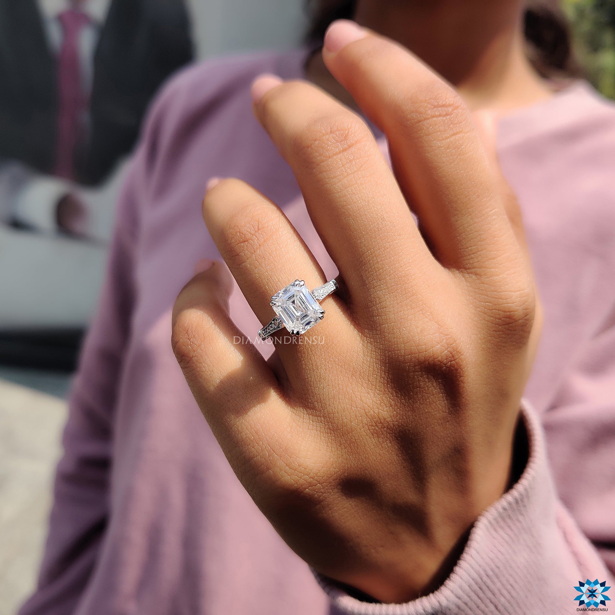 Moissanite engagement ring in cathedral setting with emerald cut and milgrain design.

