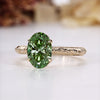 Oval cut engagement ring with green diamond solitaire.