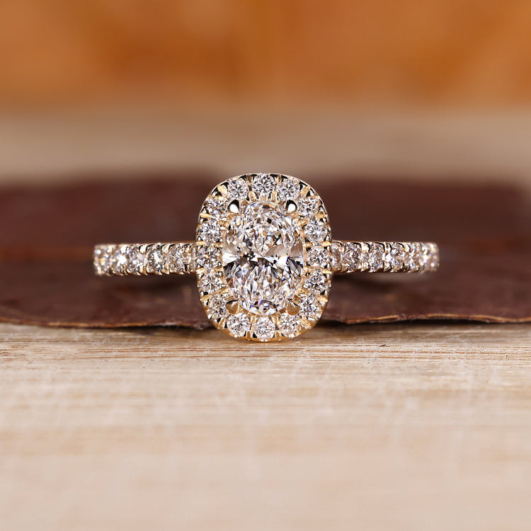 Oval diamond halo ring with round pave accents.
