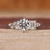 White gold engagement ring with round and emerald diamonds.
