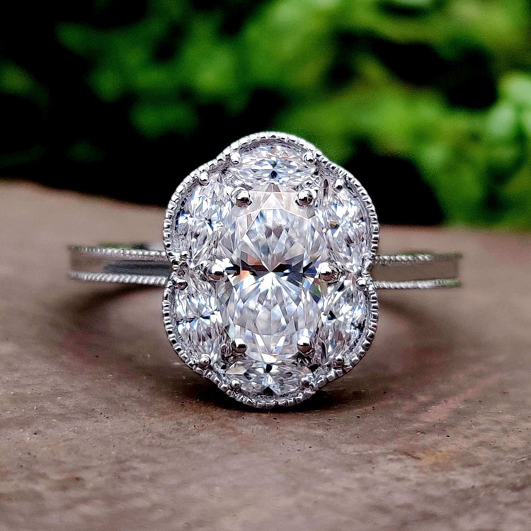 Oval moissanite cluster ring with halo and marquise accents.
