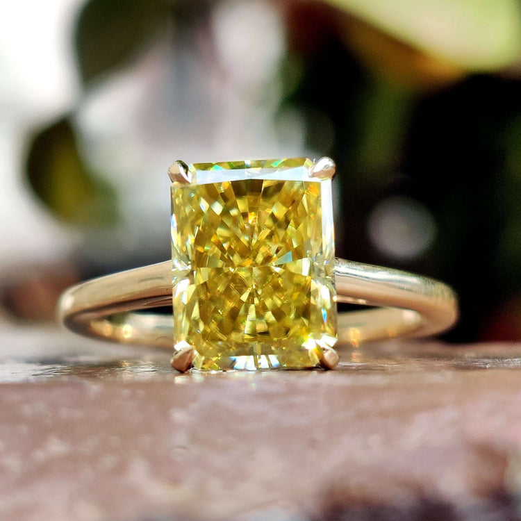 Radiant cut canary yellow moissanite ring in yellow gold.
