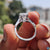 Milgrain ring featuring emerald cut moissanite and round side stone accents.
