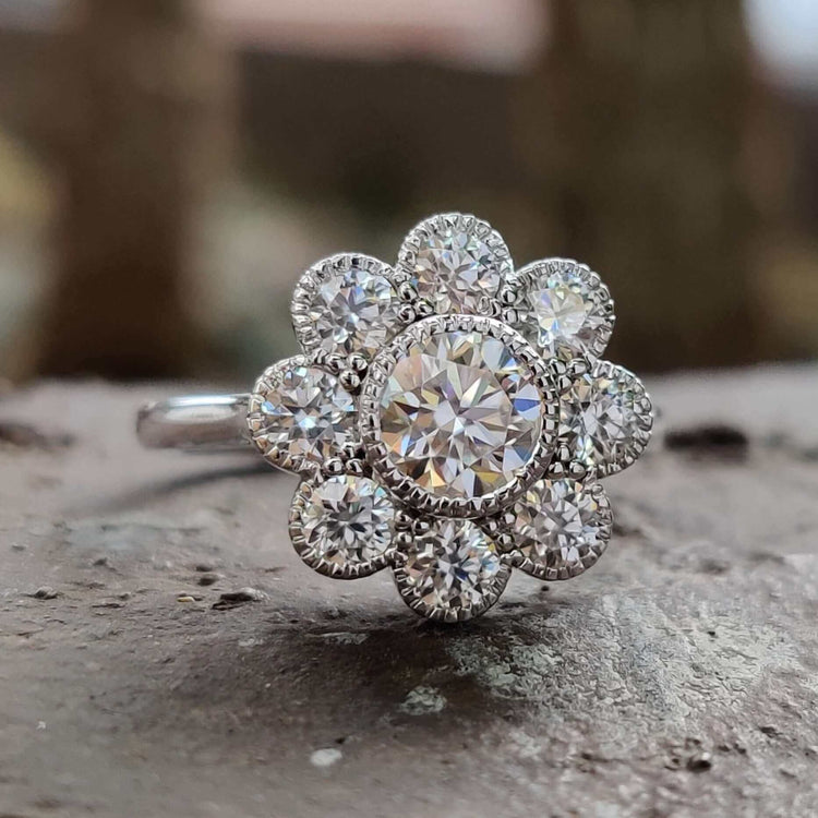 Bezel set engagement ring with round brilliant cut moissanite and halo detail.
