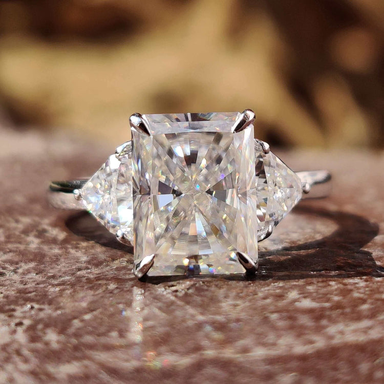 Radiant cut three stone engagement ring with trillion side stones.
