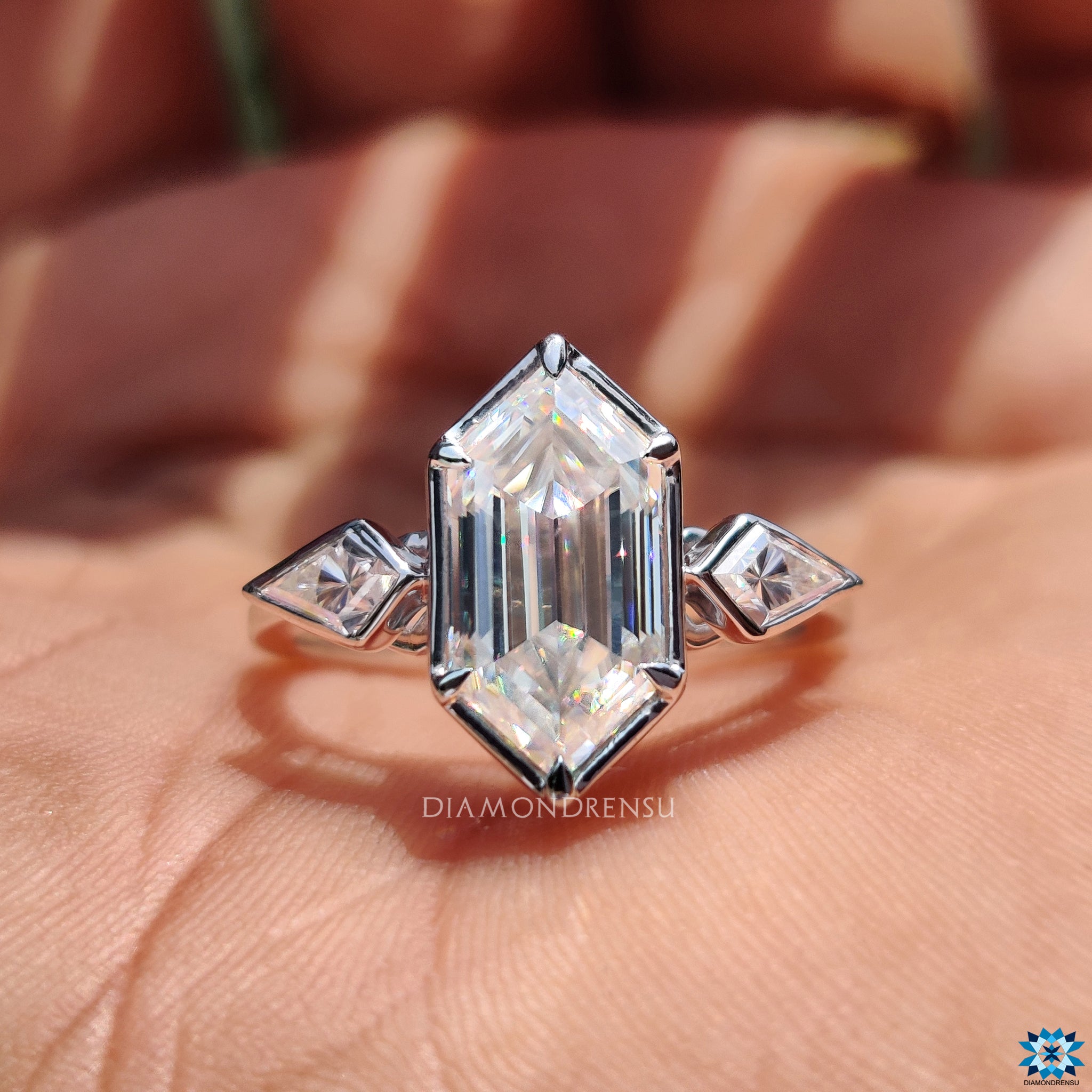 Bezel setting securing hexagon moissanite with kite cut accents.

