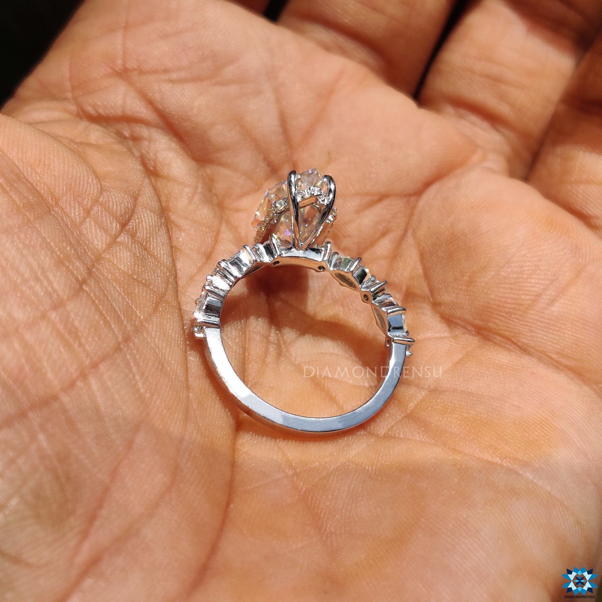 White gold engagement ring with marquise and round side moissanite stones.
