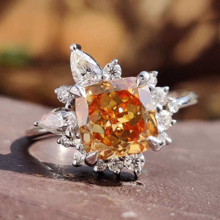 Cushion Rensu cut champagne moissanite ring with round and pear side stones.
