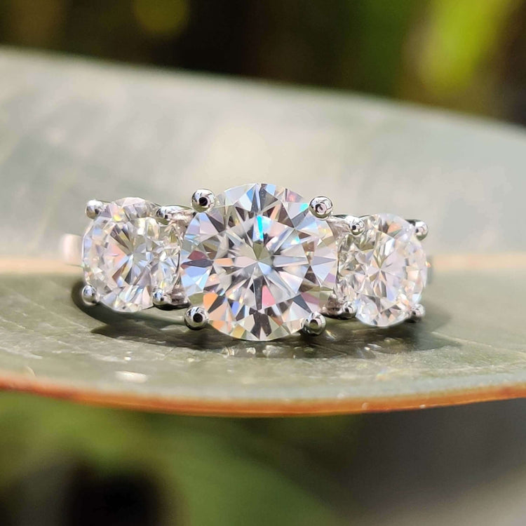 Round cut three stone moissanite engagement ring in white gold.
