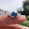 Blue moissanite engagement ring with tapered baguette side stones.
