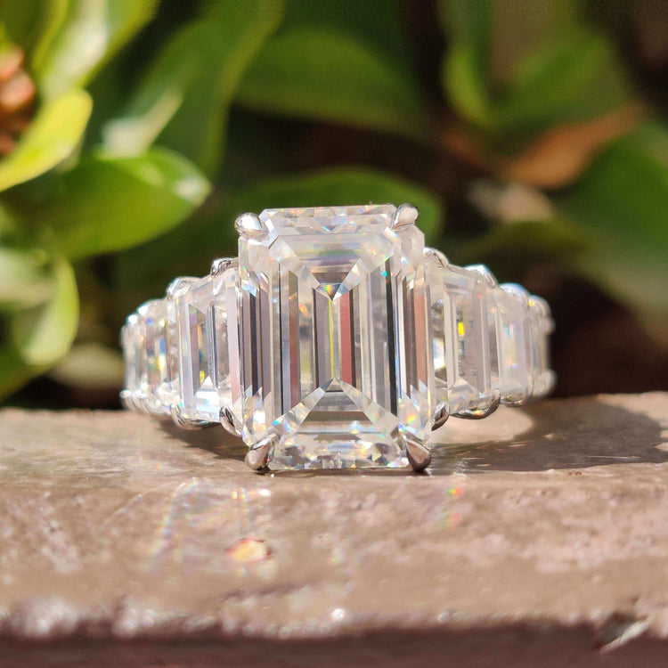Emerald cut moissanite engagement ring with pave setting in white gold.
