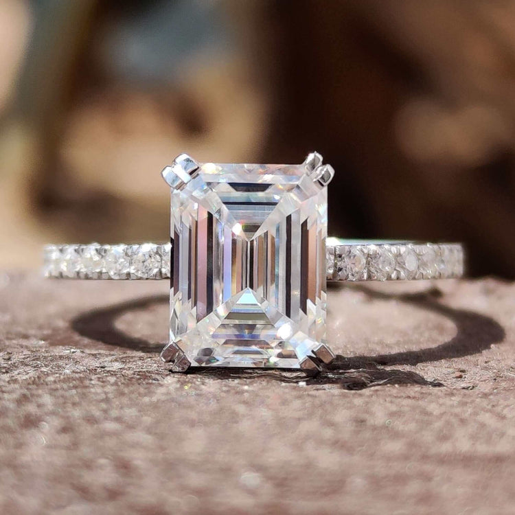 Emerald cut moissanite engagement ring with pave band in white gold.
