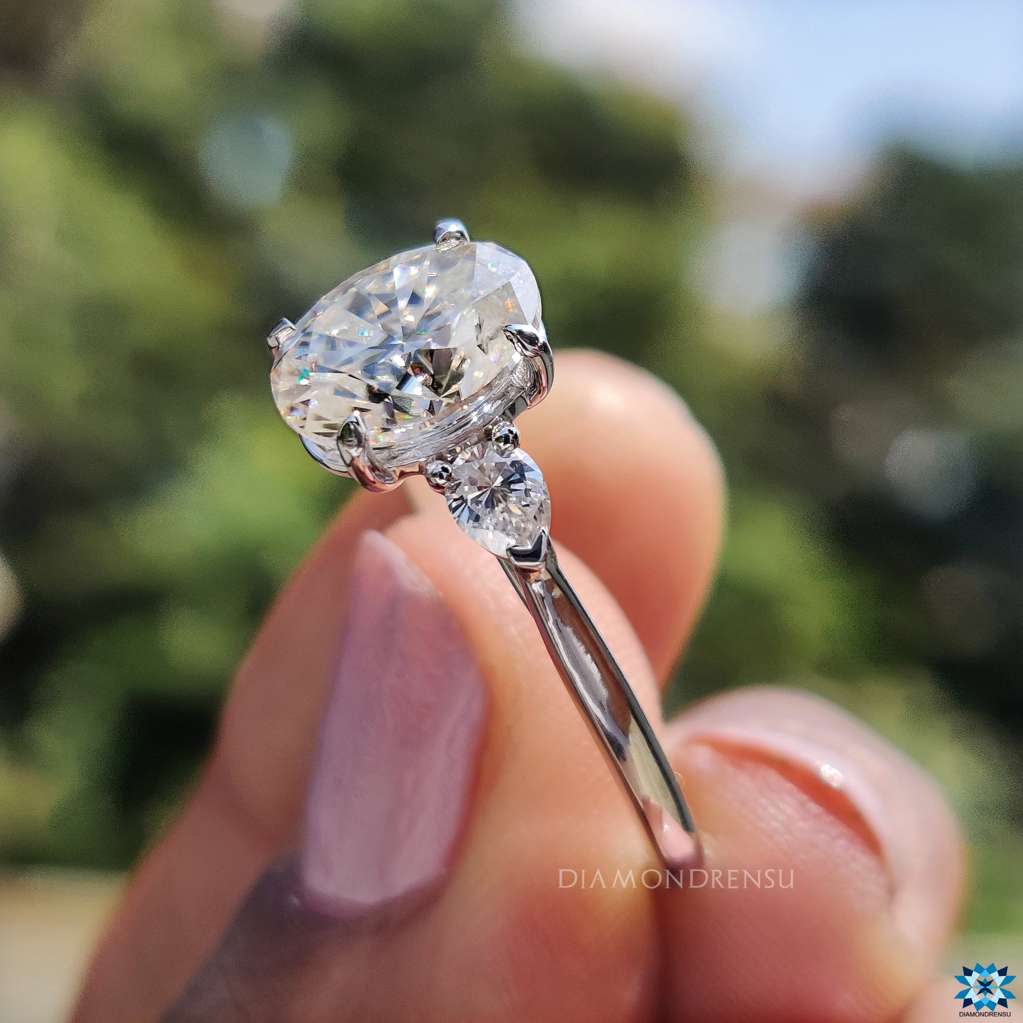 White gold engagement ring with oval and pear moissanite stones.
