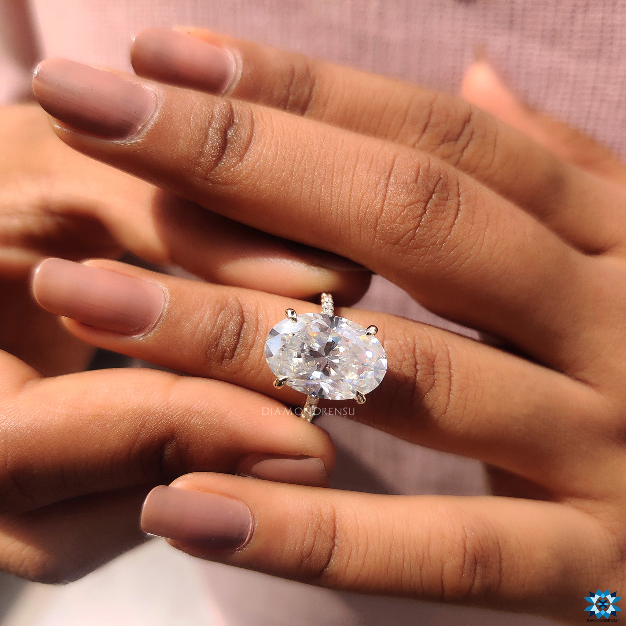 UK engagement ring with yellow gold band and oval moissanite in hidden halo setting.
