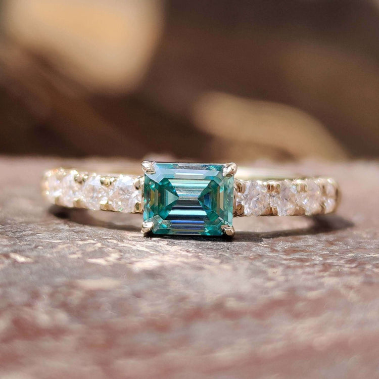 East west emerald cut moissanite ring in yellow gold.
