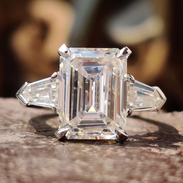 Emerald cut moissanite engagement ring with bullet cut side stones in white gold.
