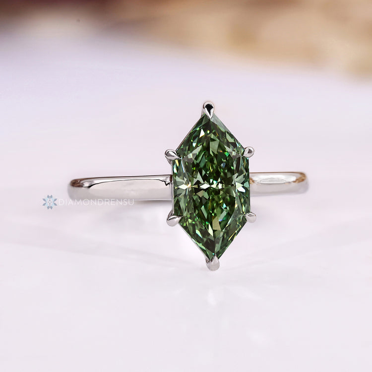 Green centre diamond ring with six claw prongs.