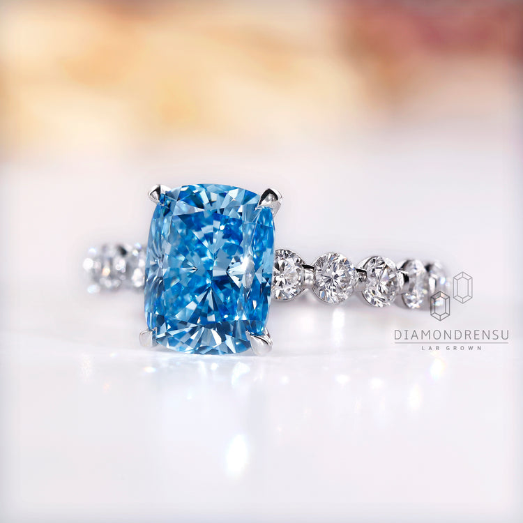 Blue diamond ring with cushion cut and claw prong setting.