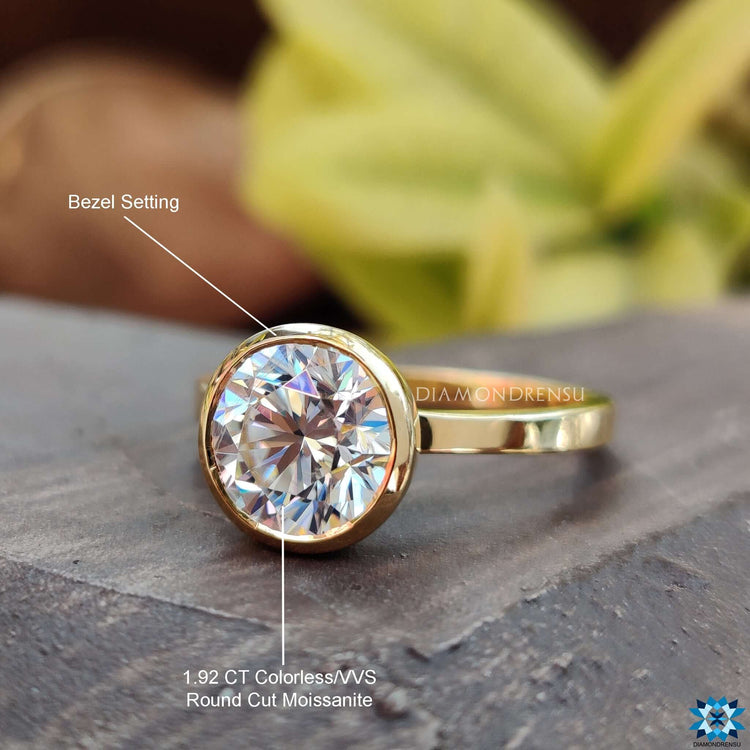 Moissanite engagement ring with bezel mount and sleek round cut center.
