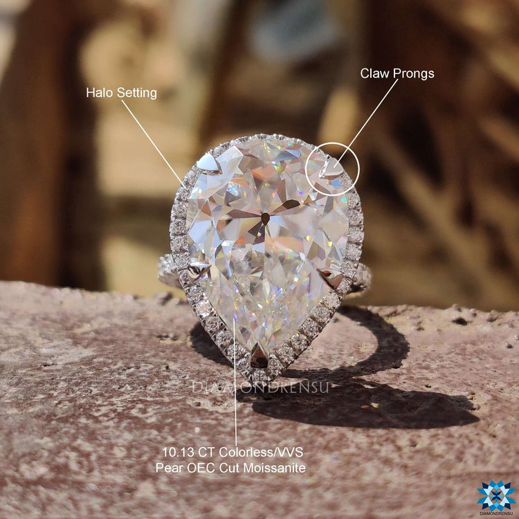 White gold ring featuring pear shape moissanite and round pave band.
