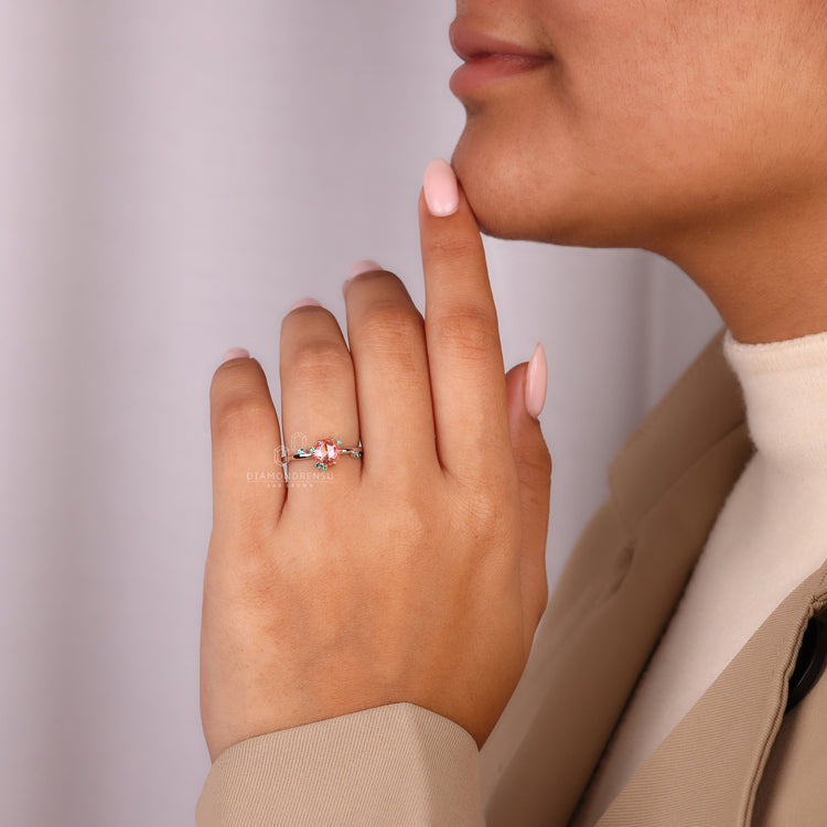 Handmade peach sapphire ring with emerald side gemstones.