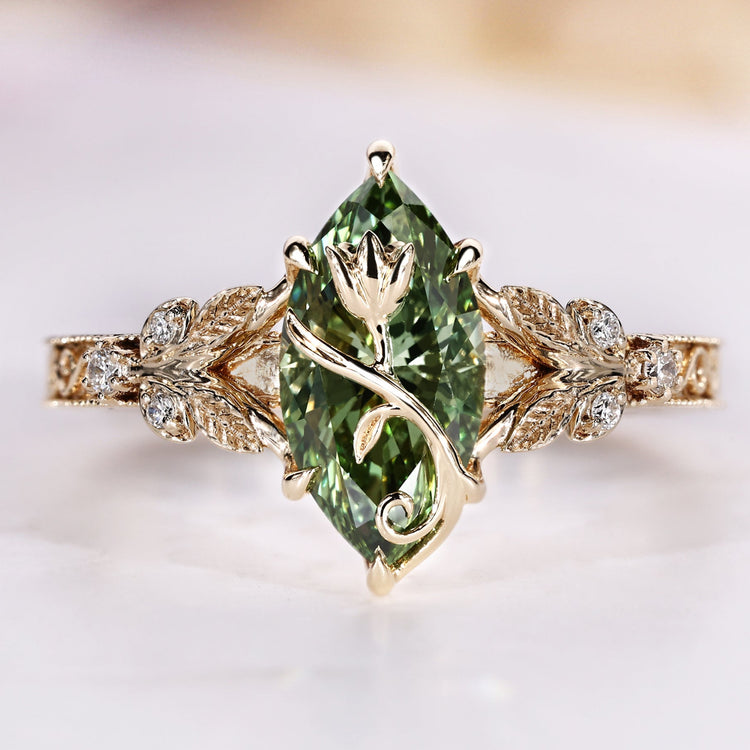 Marquise cut ring with green centre diamond and round side stones.