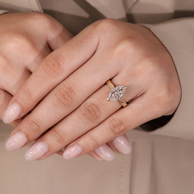 Tapered shank marquise diamond ring with milgrain detailing.