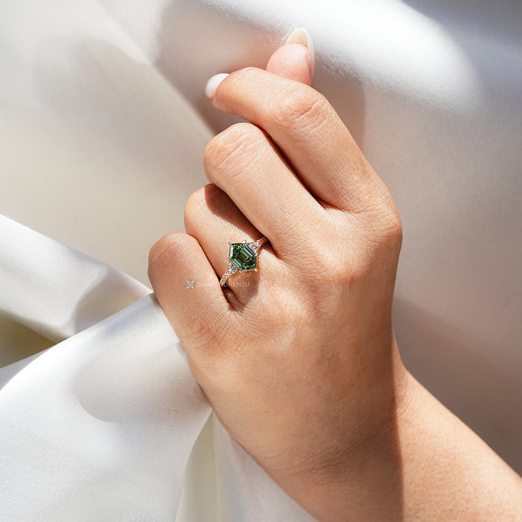 Three stone hexagon ring with green centre diamond.