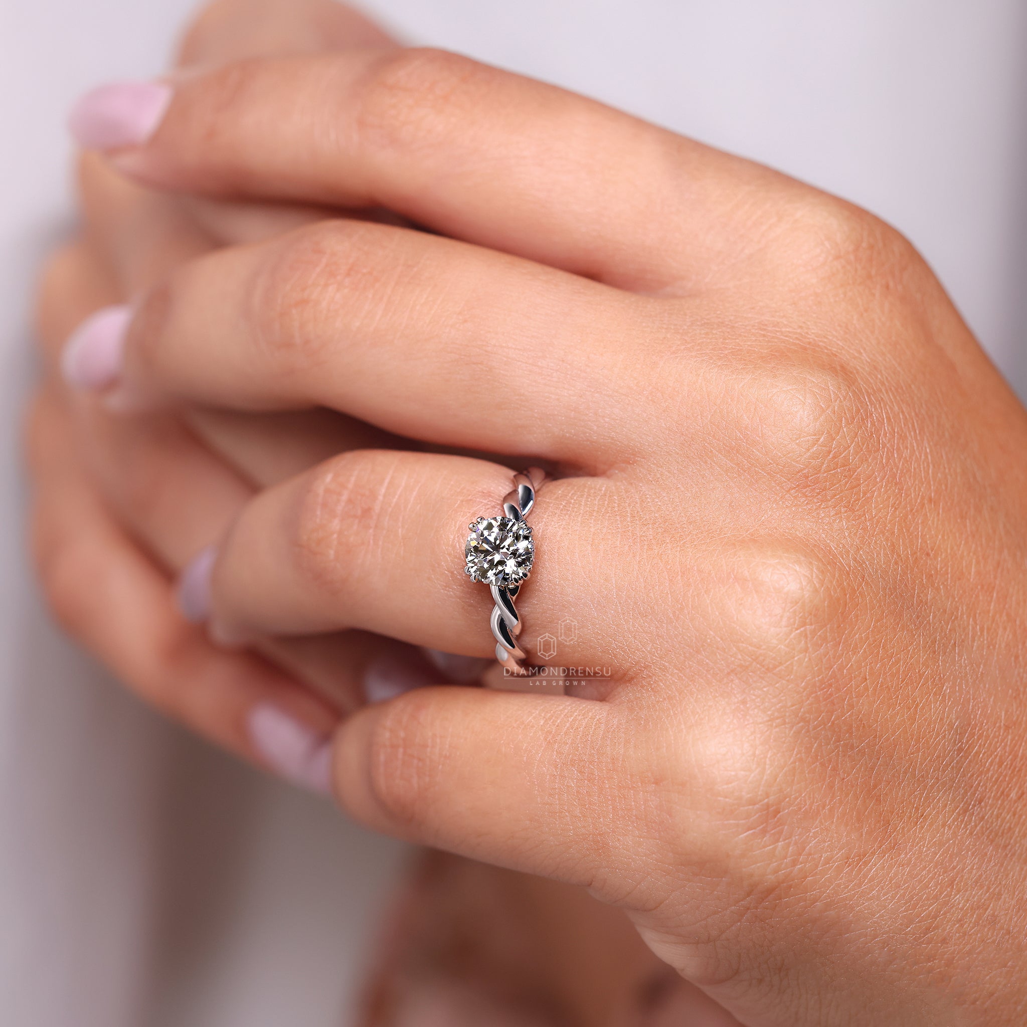 Round cut hidden halo ring with twisted setting.

