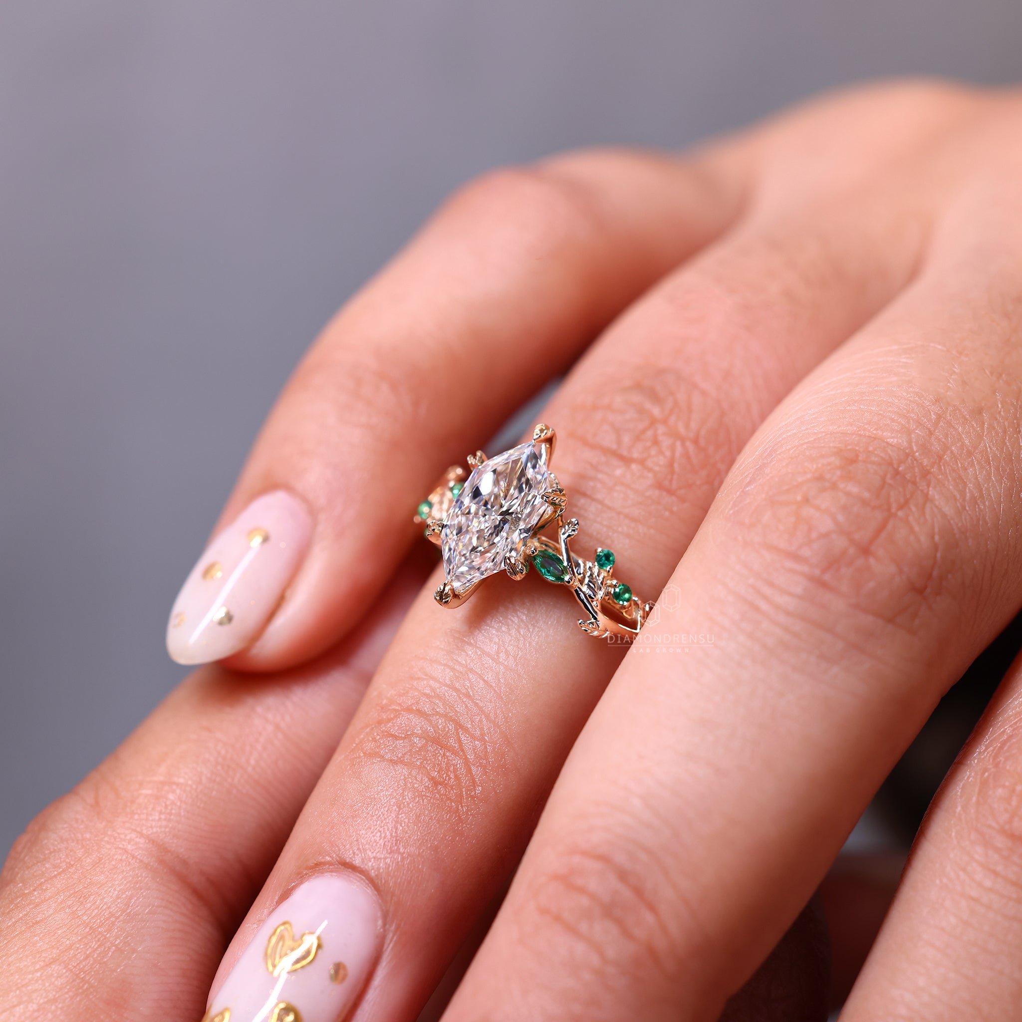 Nature inspired engagement ring featuring marquise and round emerald gemstones.
