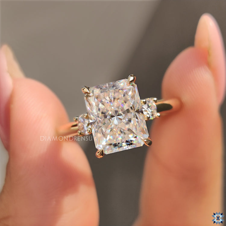 Handmade ring with radiant moissanite and round side stones in yellow gold.
