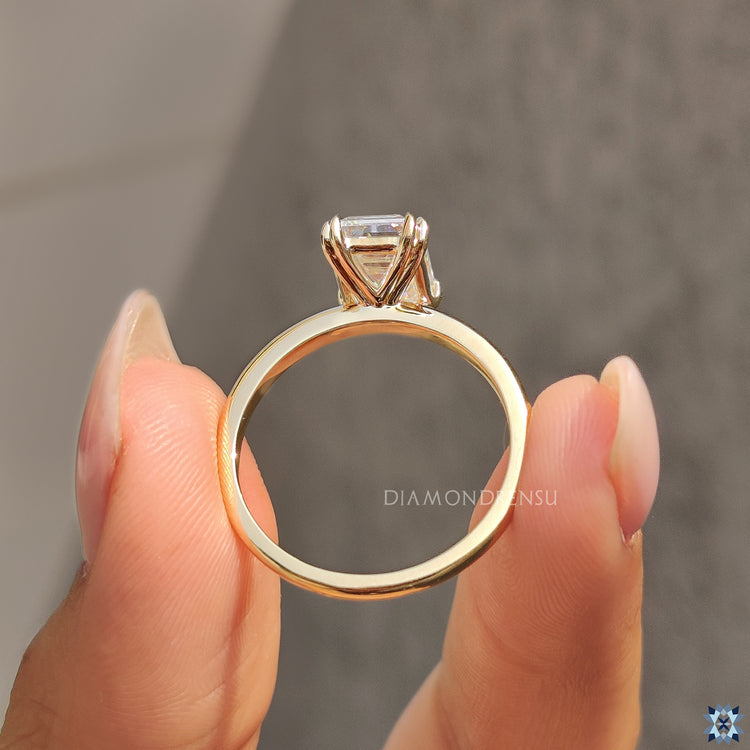 Double claw prong ring with emerald cut moissanite and custom design.
