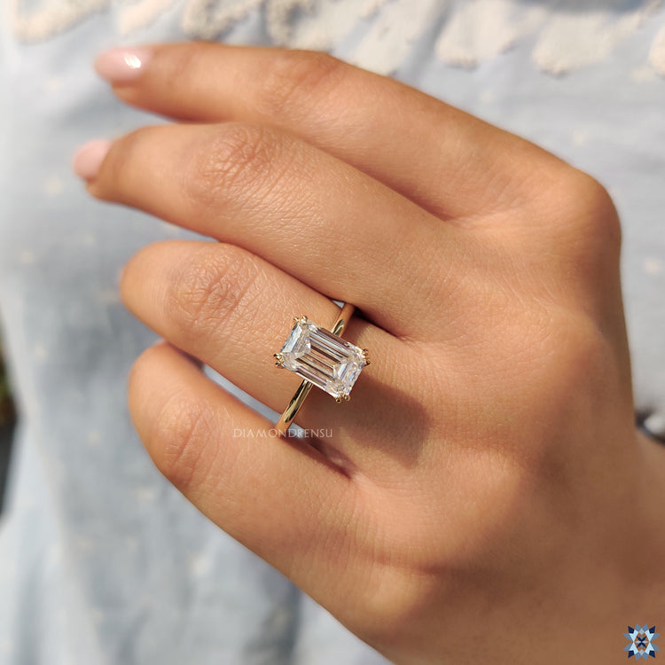 Emerald cut solitaire ring set in yellow gold with handmade details.
