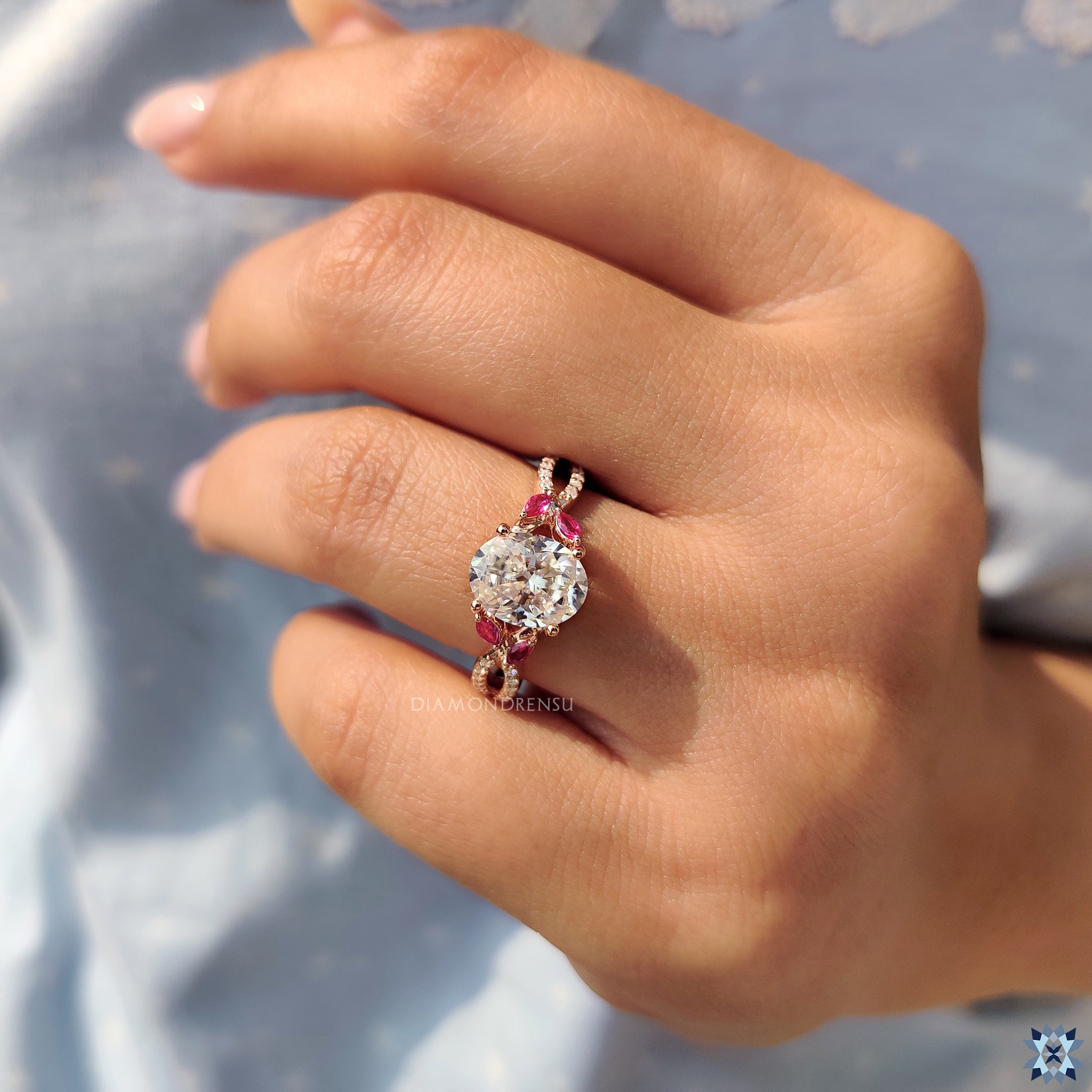 Moissanite engagement ring featuring twisted pave design and red marquise accents.
