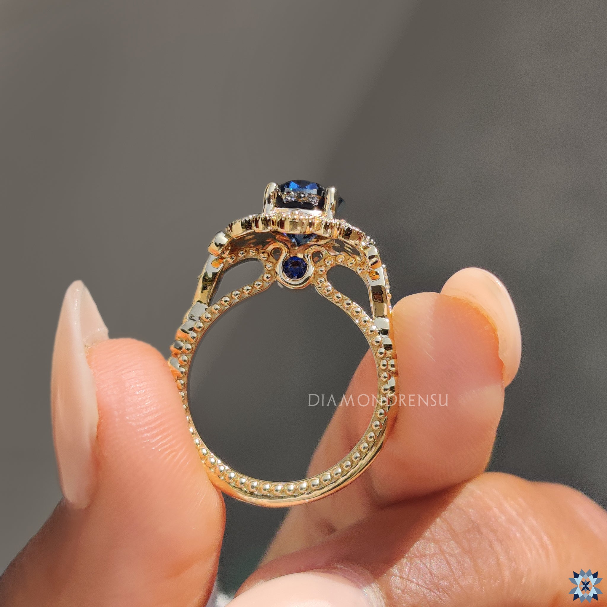 Blue round moissanite ring with art deco design and milgrain border.
